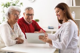 Picture of senior couple talking with clinician and looking at computer